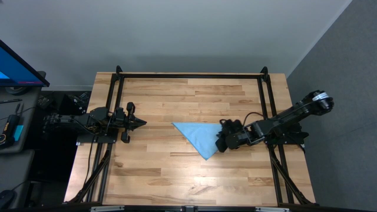 Original towel-folding recording: a blue triangular towel on a wooden table between two robot arms